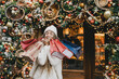 © polinaloves - Young beautiful womam enjoying Christmas shopping on a decorated street.