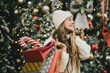 © polinaloves - Young beautiful womam enjoying Christmas shopping on a decorated street.