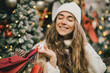 © polinaloves - Young beautiful womam enjoying Christmas shopping on a decorated street.