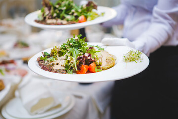 Waiter serving fresh salads at a banquet in spring.