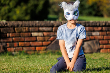 Cute young little kid girl wear cat furry mask enjoy have fun playing outdoors in forest street park. Children therian wild animal character trendy fan culture. Teenager social expression hobby