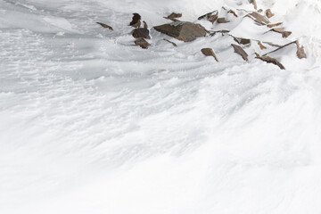 Wall Mural - brown rocks covered by white winter windswept snow background