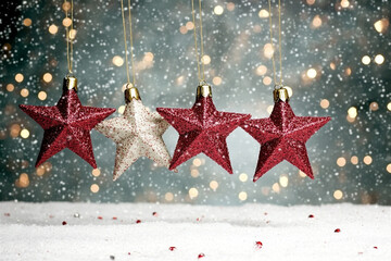 Wall Mural - Four christmas stars hanging with a string lights background with snow falling creating a magical christmas feeling