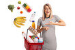 © Ljupco Smokovski - Woman holding a shopping basket with products falling inside the basket