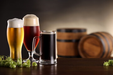 Poster - Glasses with different types of beer and fresh hops on wooden table in bar. Space for text