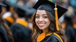 © 69 - A female graduate in cap and gown, smiling confidently while standing in a crowd of students during a graduation ceremony.