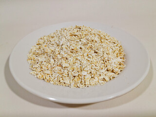 oat, oat grains, oat flakes in a white plate, isolated on white background and close up shot.