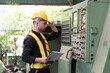 © amorn - Male engineer control CNC machine in factory. Male technician working and repairing or maintenance CNC machine with safety uniform, helmet in industry factory
