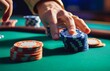 © clairelucia - A hand placing a stack of poker chips on a green table
