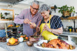 © Marcos - Latin senior couple cooking a turkey meat together for Christmas dinner at home in Mexico Latin America, hispanic people preparing food in thanksgiving holidays