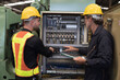 © amorn - Two male electrician checking, repair, maintenance electric system board of CNC machine in factory. Group of male electrician engineer inspecting electric system during manufacturing process