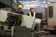 © amorn - Two male engineer checking, repair, maintenance CNC machine in factory. Group of male technician working with CNC machine during manufacturing process
