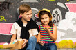 © zulfiska - Kids eating colorful sweet and tasty donuts. Children snacking on unhealthy food outdoors.