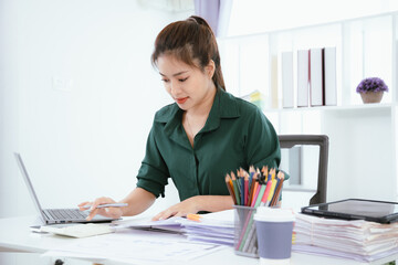 Confident Asian businesswoman in her office checking financial reports on her laptop. Analyzing data, planning strategies and full of success, professionalism and entrepreneurial spirit.