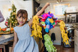 © Marcos - latin child girl holding a mexican pinata at home in Mexico celebrating traditional posadas for Christmas in Latin America