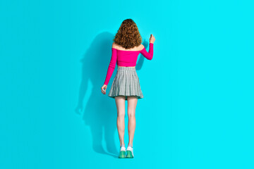 Poster - Full body rear portrait of nice young girl empty space board wear top isolated on turquoise color background