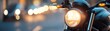© TENTIP - Close-up of a motorcycle headlight with blurred city lights in the background, highlighting urban night riding and adventure.