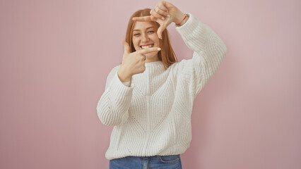 Sticker - A smiling young caucasian redhead woman wearing a sweater poses playfully over a pink isolated background.