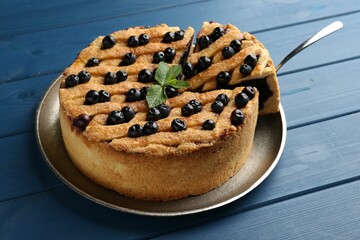 Taking slice of homemade blueberry pie on blue wooden table, closeup