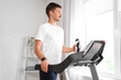 © Pixel-Shot - Sporty young man training on treadmill at home