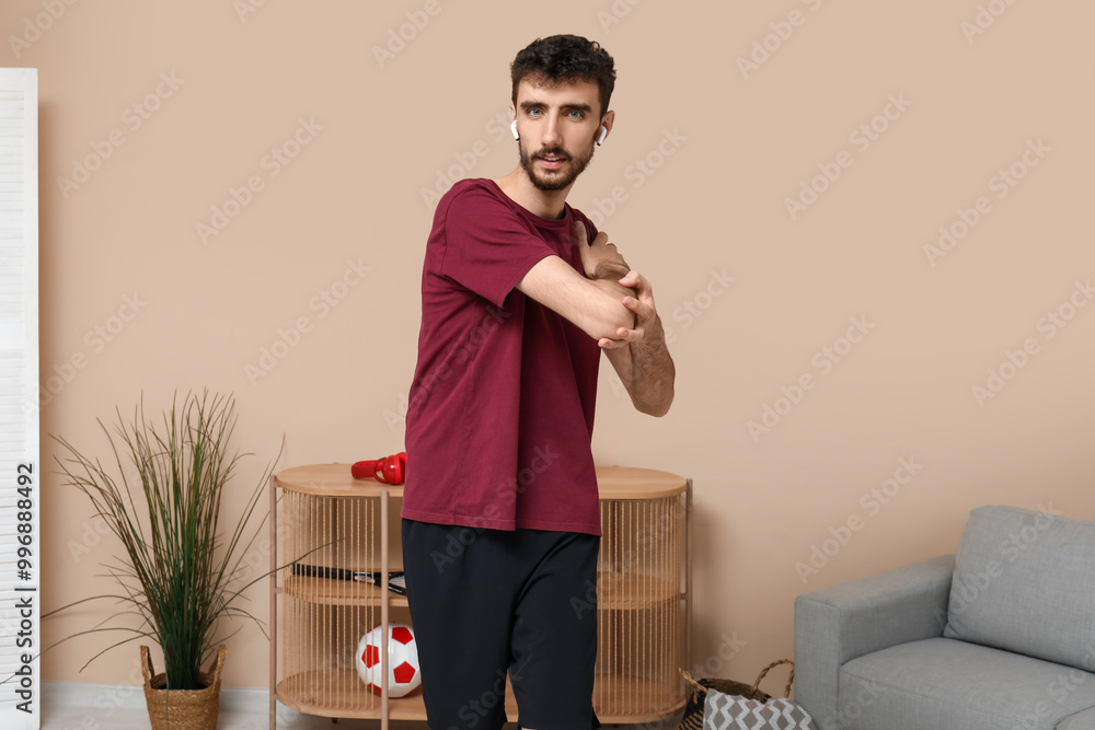 Sporty young man in earphones training at home