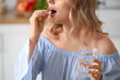 © Pixel-Shot - Young woman with glass of water taking pill in kitchen, closeup