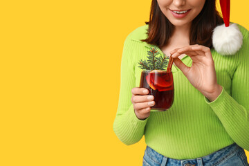 Poster - Young woman with glass of hot mulled wine on yellow background