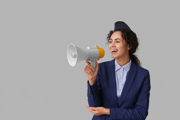 Canvas Print - Beautiful young African-American stewardess with megaphone on grey background