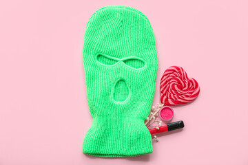 Wall Mural - Composition with balaclava, lollipop and cosmetics on pink background