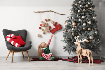 Poster - Cute little girl sitting on floor in living room decorated for Christmas celebration