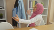 © Krakenimages.com - A smiling woman wearing a hijab holds a coffee cup and takes a selfie with a smartphone in a cozy room.