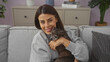 © Krakenimages.com - Smiling young woman cuddling with her pet chihuahua on the couch indoors in a cozy home setting
