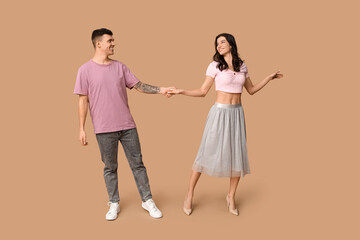 Poster - Happy young couple dancing on brown background