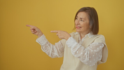 Poster - A smiling middle-aged woman points enthusiastically against a yellow background wearing a white blouse.