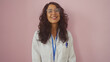© Krakenimages.com - A smiling hispanic woman in a white lab coat with glasses against a pink background.