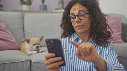 Sticker - Hispanic woman using smartphone in living room with sleeping chihuahua on couch