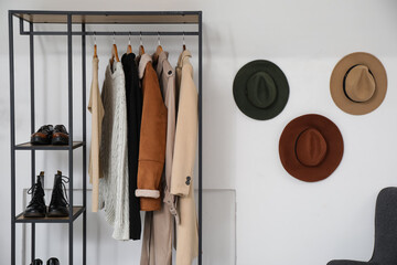 Canvas Print - Clothes rack with shoes and hanging hats on light wall in dressing room