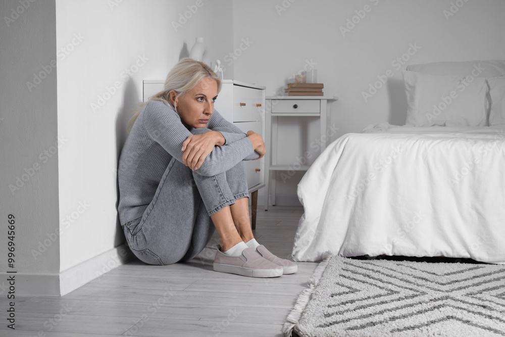 Mature woman having panic attack on floor in bedroom