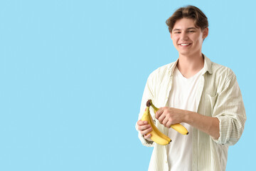 Wall Mural - Young man with bananas on blue background