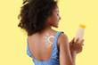 © Pixel-Shot - Little African-American girl with sun made of sunscreen cream on her back against yellow background