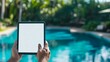 © Khalil - Man using tablet by the pool, blank white mock up screen
