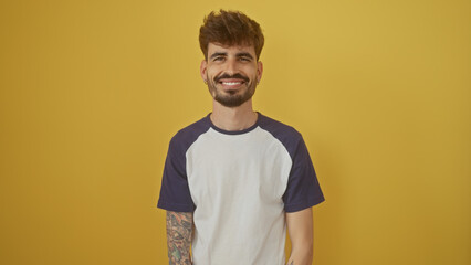 Poster - Handsome young man with beard and tattoos smiling confidently against a vibrant yellow background