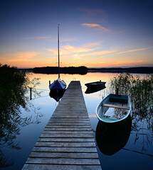 Wall Mural - Wooden Pier at calm lake with boats at sunset