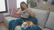 © Krakenimages.com - A young woman makes a heart sign while sitting with her chihuahua on a couch indoors.