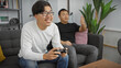 © Krakenimages.com - Two asian men enjoying time together playing video games in a cozy living room setting.