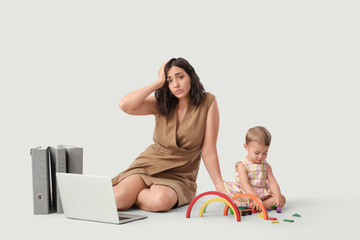 Sticker - Tired businesswoman and her little baby playing with toys on light background