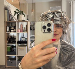 Woman making Selfie Picture using Mobile Phone at Hairdresser Salon. Beautiful Female Admire her new Hairstyle on Long Hair, sending video message