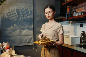 Wall Mural - Woman holding a plate of food in the kitchen and looking at the camera