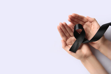 Wall Mural - Female hands with black ribbon on white background. World Cancer Day