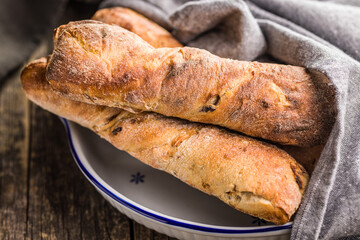 Canvas Print - Crusty rustic baguette in bowl on wooden table.